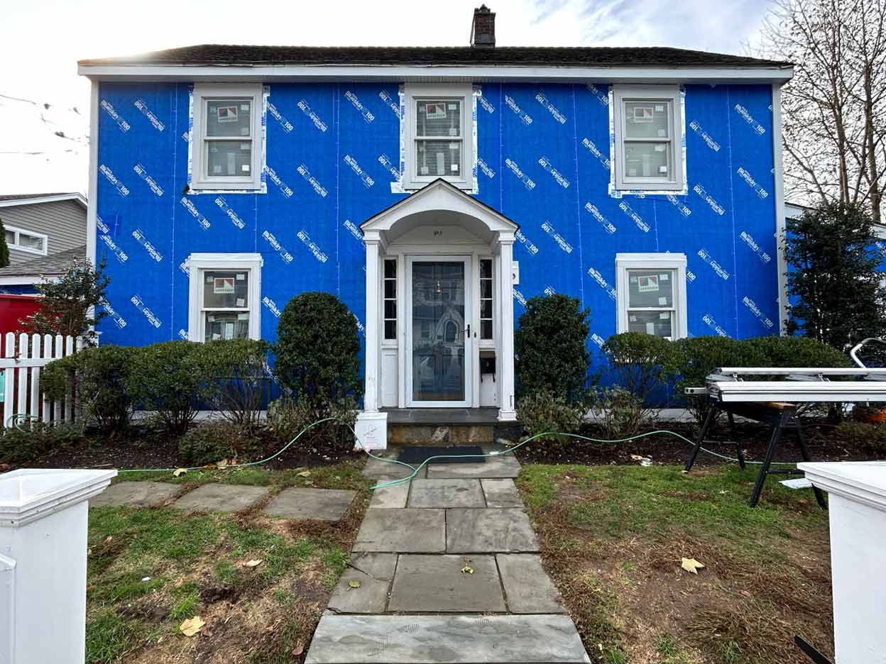 Home with blue house wrap and freshly installed windows