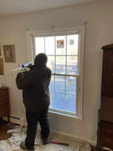 A window contractor applies caulk to newly installed windows