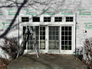 Newly installed windows and patio doors with siding installation in progress