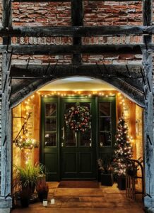 Green door with lights and Christmas tree and wreath.
