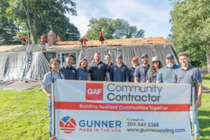 Gunner team standing in front of home being re-roofed for Habitat for Humanity